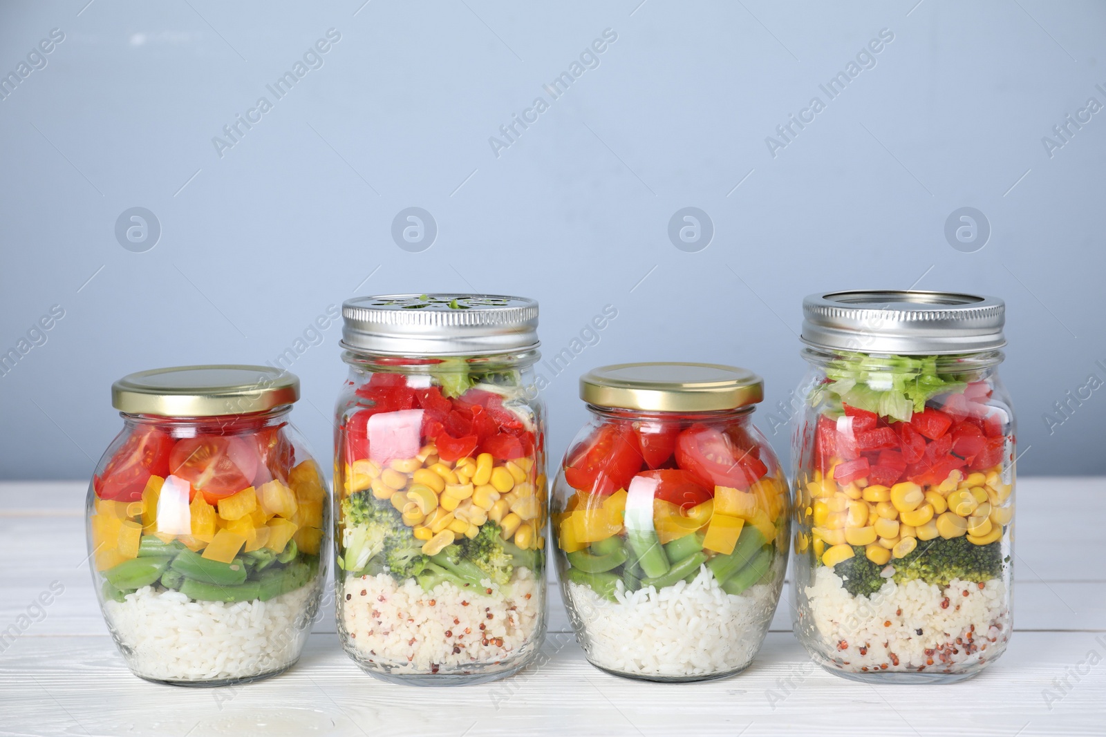 Photo of Glass jars with healthy meal on white wooden table