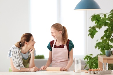 Mother and her daughter making dough at table in kitchen