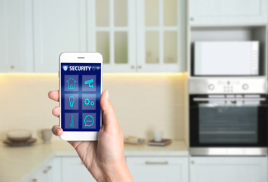 Woman using home security app indoors, closeup. Space for text