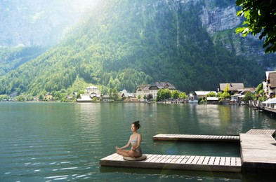 Image of Woman meditating at riverside near beautiful mountain, space for text