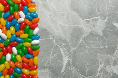 Delicious bright jelly beans on stone background, top view. Space for text