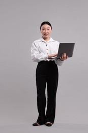 Photo of Full length portrait of smiling businesswoman with laptop on grey background