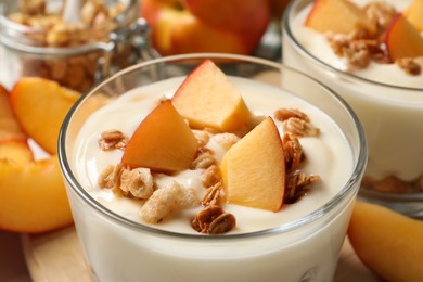Photo of Delicious yogurt with fresh peach and granola in glass, closeup