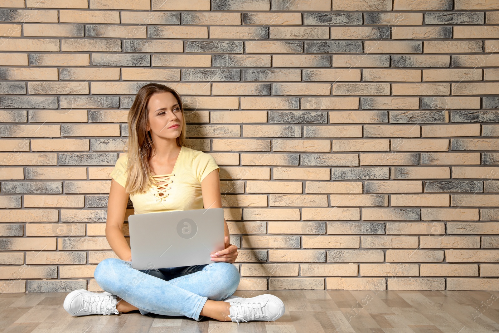 Photo of Portrait of beautiful woman with laptop near brick wall