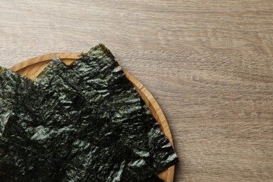 Plate with dry nori sheets on wooden table, top view. Space for text