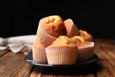 Delicious sweet muffins on wooden table against dark background, closeup