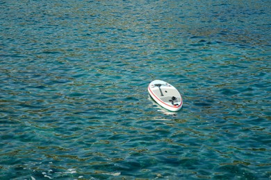 Photo of One SUP board with paddle on sea water, space for text