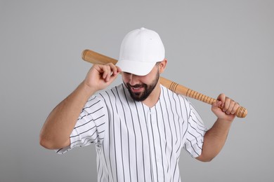 Photo of Man in stylish white baseball cap holding bat on light grey background