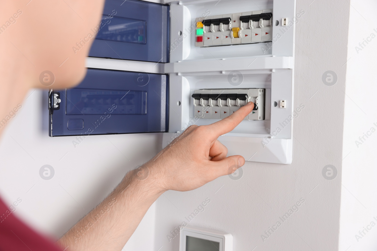 Photo of Handyman pressing switch on electrical panel board indoors, closeup