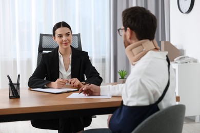 Injured man having meeting with lawyer in office, selective focus