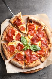 Tasty pepperoni pizza with basil on grey table, top view