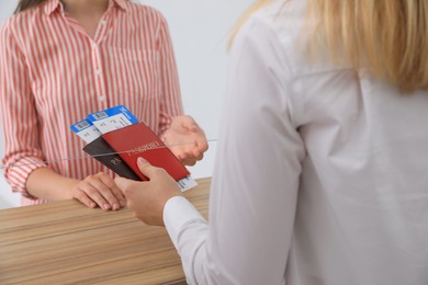 Agent giving passports with tickets to client at check-in desk in airport, closeup