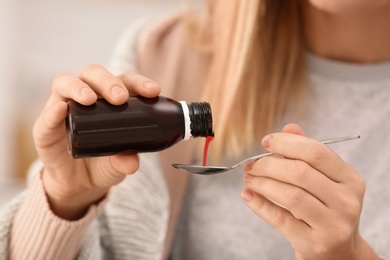 Photo of Woman taking cough syrup, closeup view