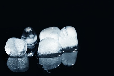 Photo of Melting ice cubes on black background. Space for text