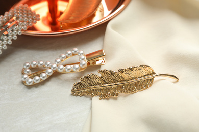 Photo of Beautiful different hair clips and fabric on white table