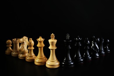 White and black chess pieces against dark background. Competition concept