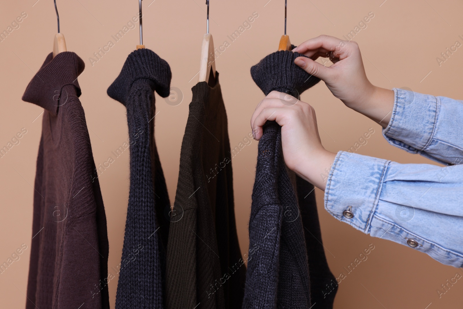 Photo of Woman taking casual sweater on beige background, closeup
