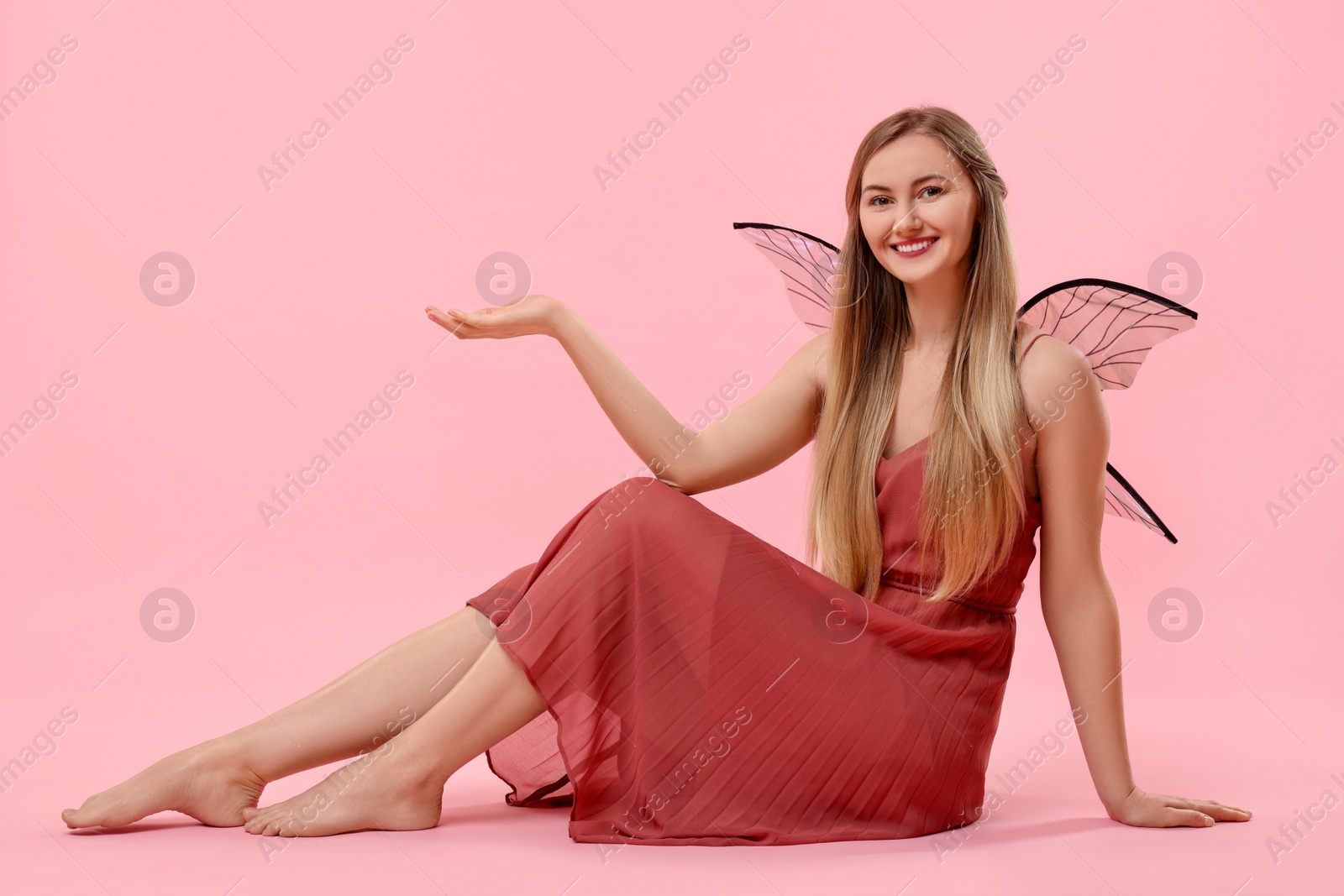 Photo of Beautiful girl in fairy costume with wings on pink background