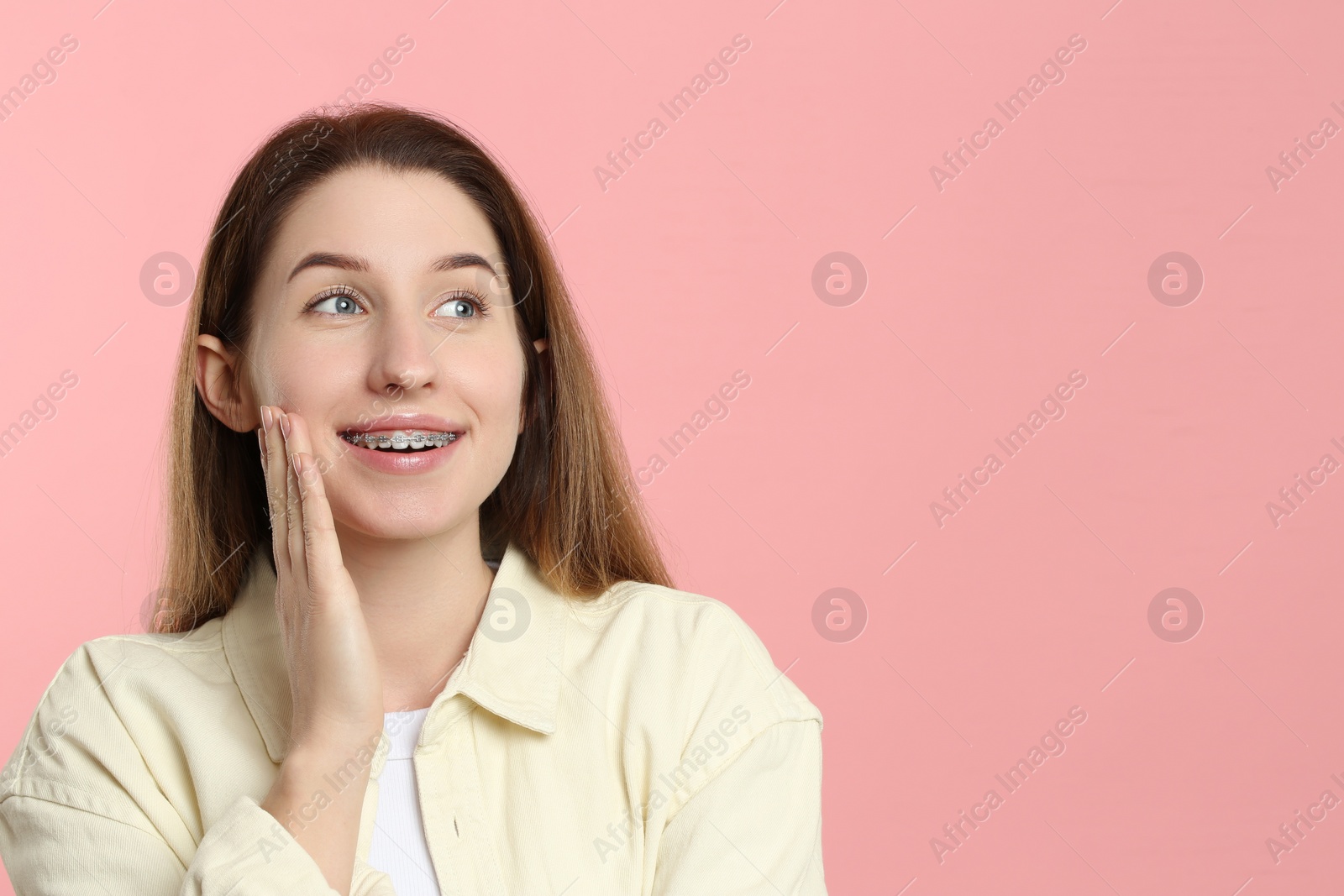 Photo of Portrait of smiling woman with dental braces on pink background. Space for text