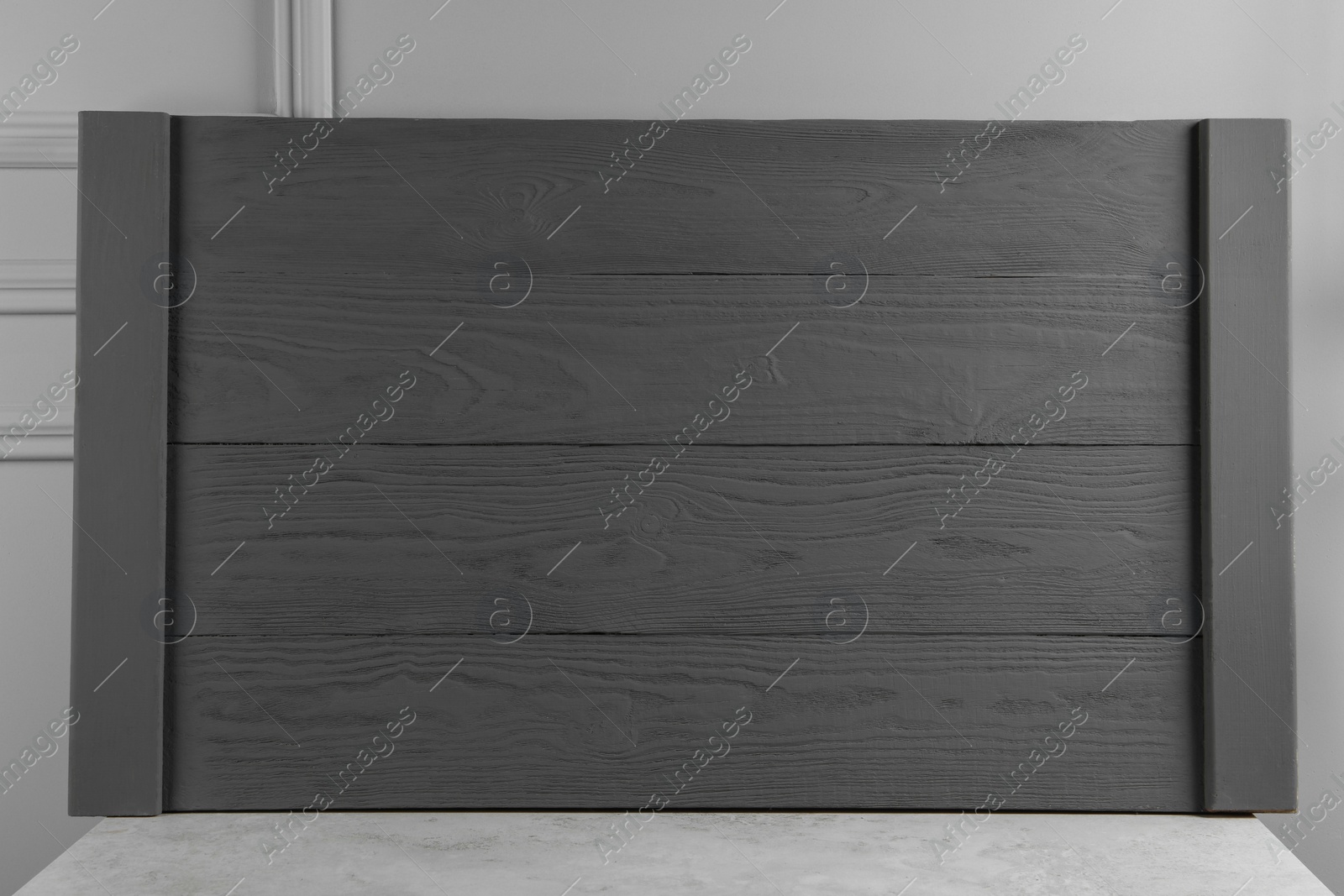 Photo of Wooden board on table near light grey wall