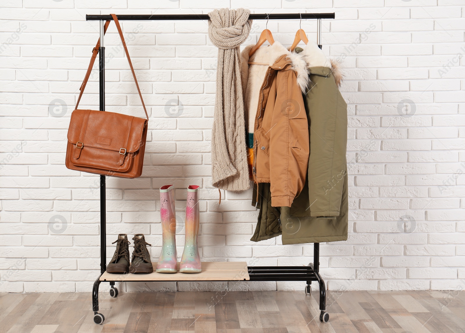 Photo of Shoes and clothes on hanger stand against brick wall. Idea for interior decor