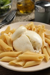 Photo of Plate of delicious pasta with burrata on wooden table, closeup