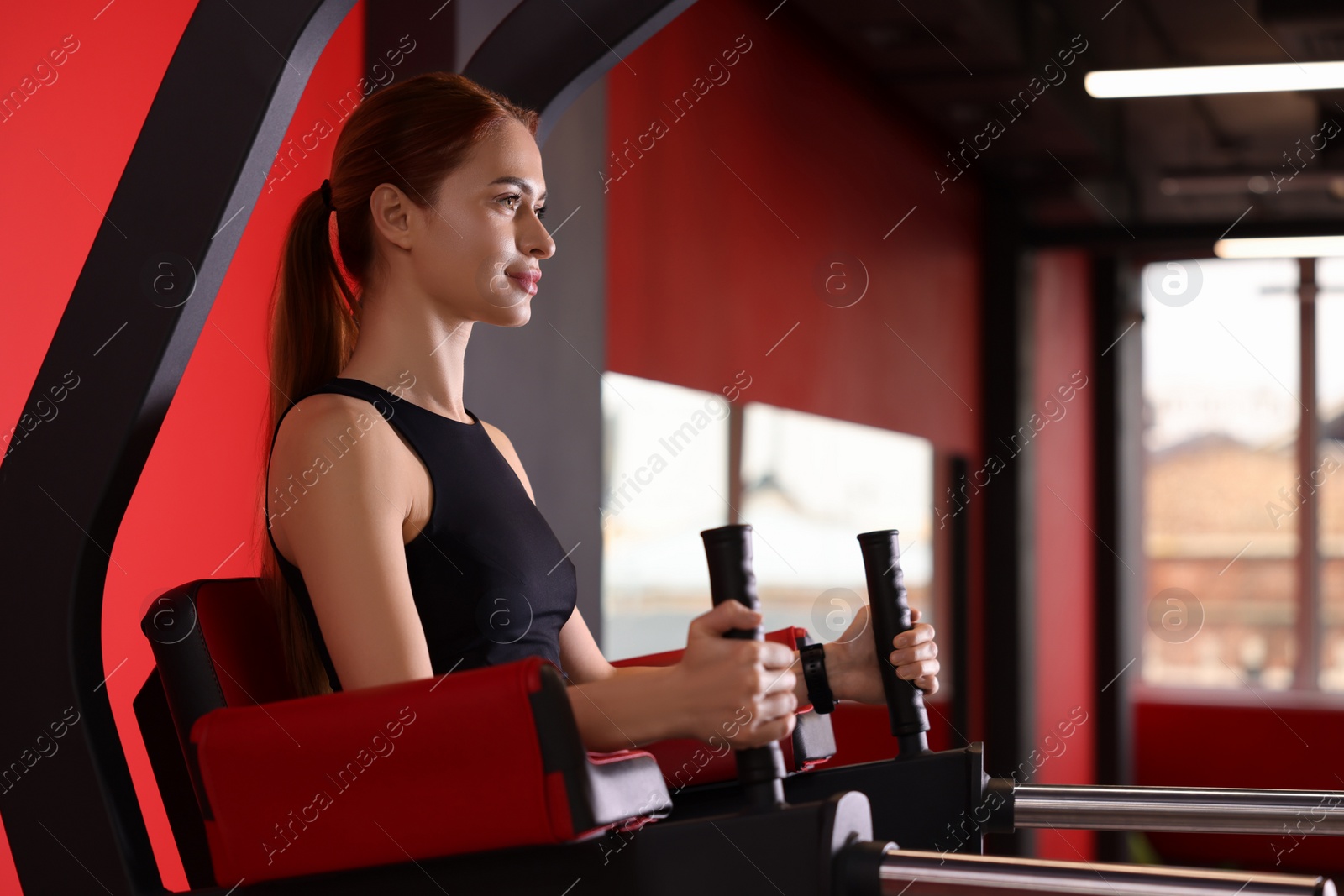 Photo of Athletic young woman training on power tower station in gym