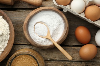 Photo of Baking powder, eggs, brown sugar and flour on wooden table, flat lay