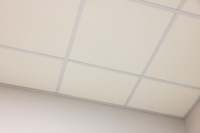 Photo of White ceiling with PVC tiles indoors, low angle view