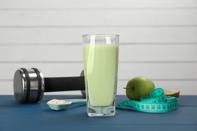 Tasty shake, dumbbell, measuring tape, powder and fruits on blue wooden table. Weight loss