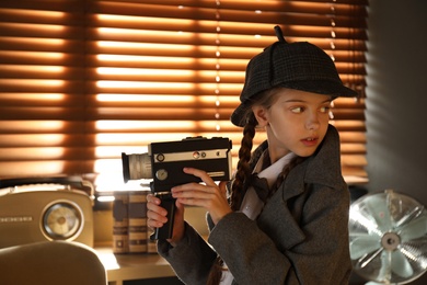 Photo of Cute little detective with vintage video camera in office