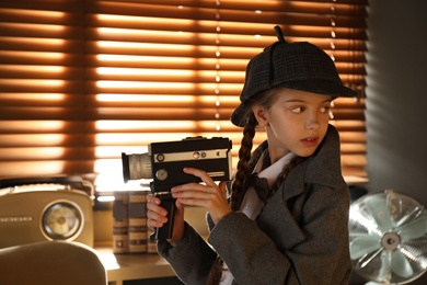 Cute little detective with vintage video camera in office