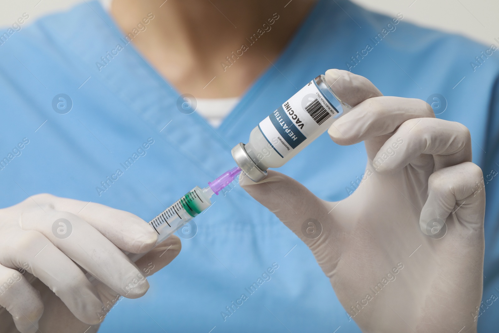 Photo of Doctor filling syringe with hepatitis vaccine from glass vial, closeup