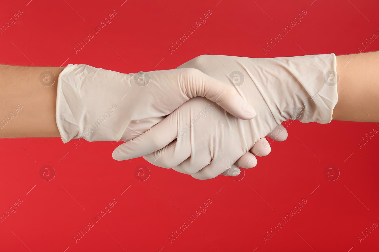 Photo of People in medical gloves shaking hands on red background, closeup