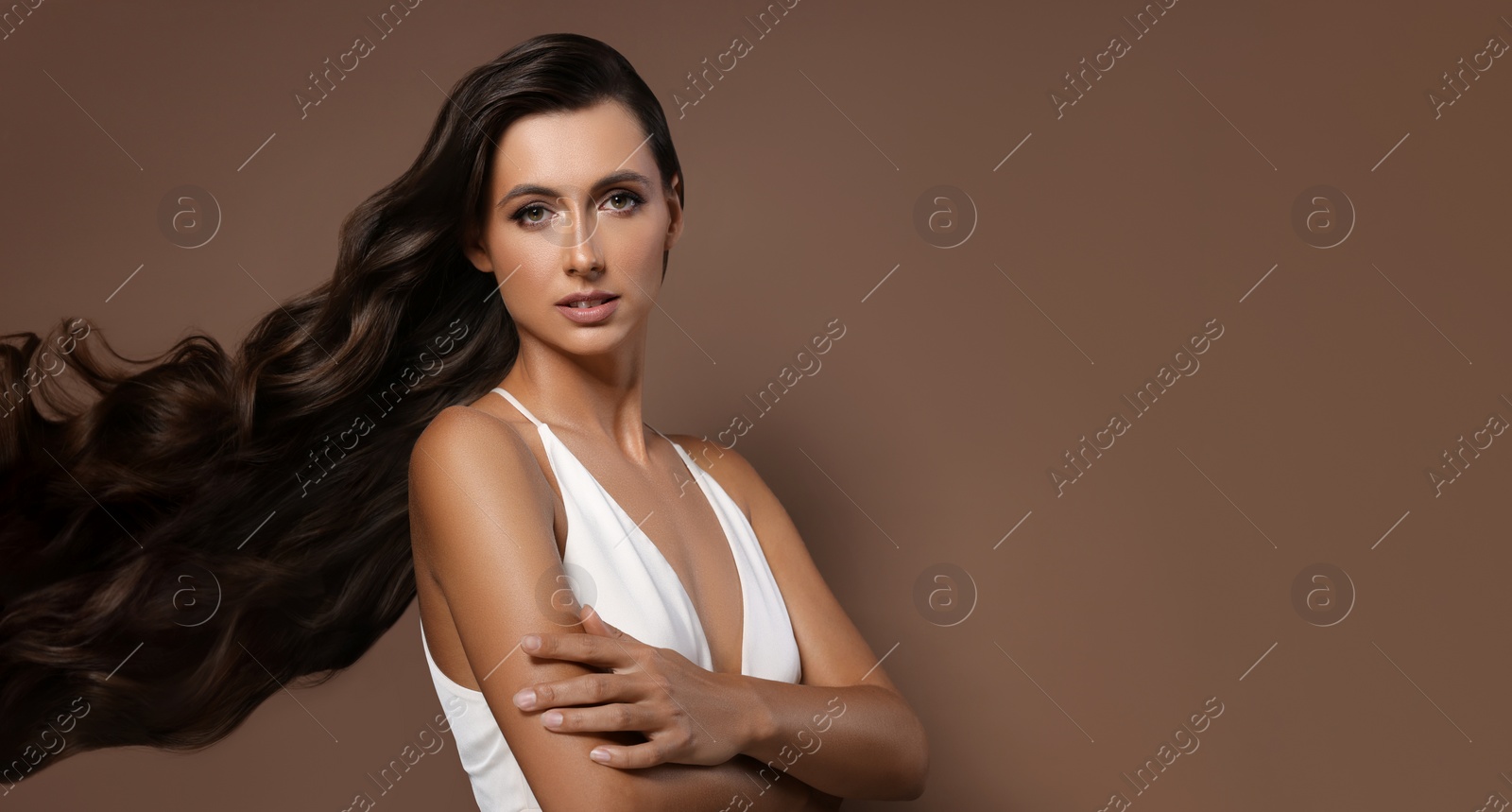 Image of Hair styling. Attractive woman with wavy long hair on brown background. Banner design with space for text