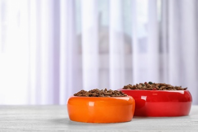 Photo of Bowls with food for cat and dog on floor. Pet care