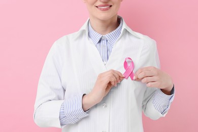 Mammologist with pink ribbon against color background, closeup. Breast cancer awareness.