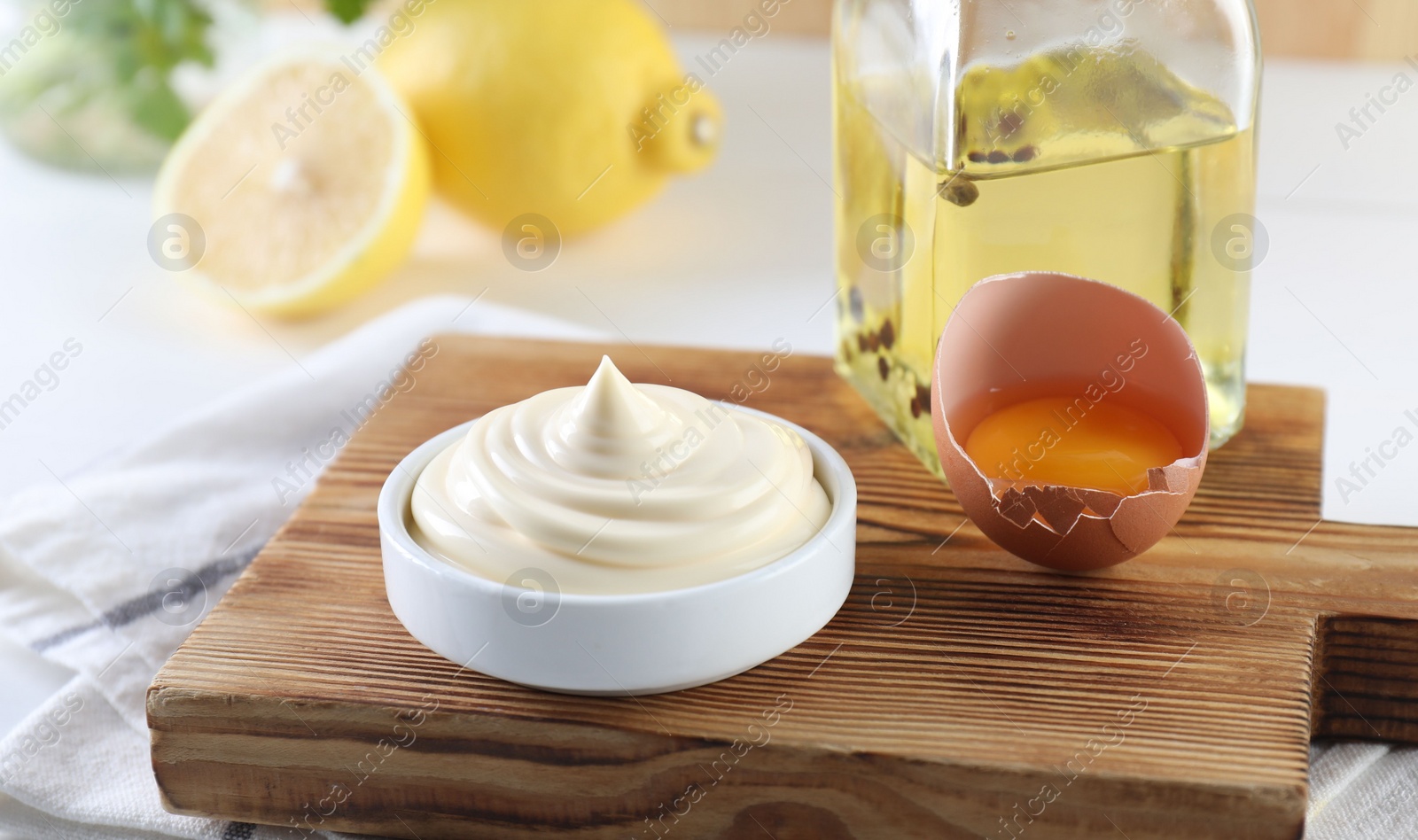 Photo of Fresh mayonnaise sauce in bowl and ingredients on table