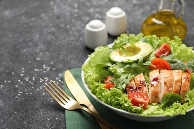 Delicious salad with chicken, cherry tomato and avocado served on grey textured table, space for text