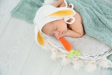 Photo of Adorable newborn child wearing bunny ears hat in baby nest