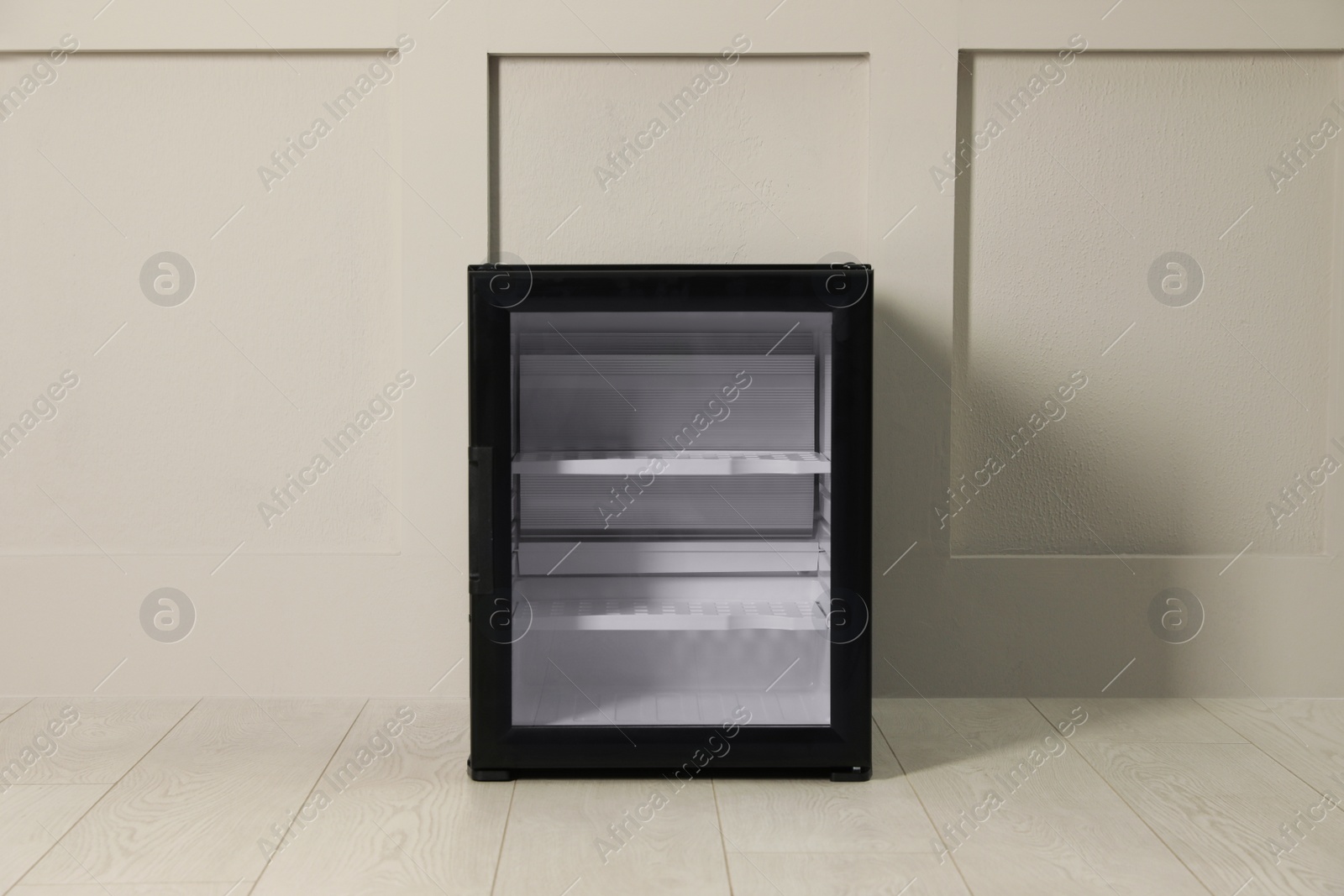 Photo of Empty mini bar with glass door near beige wall indoors