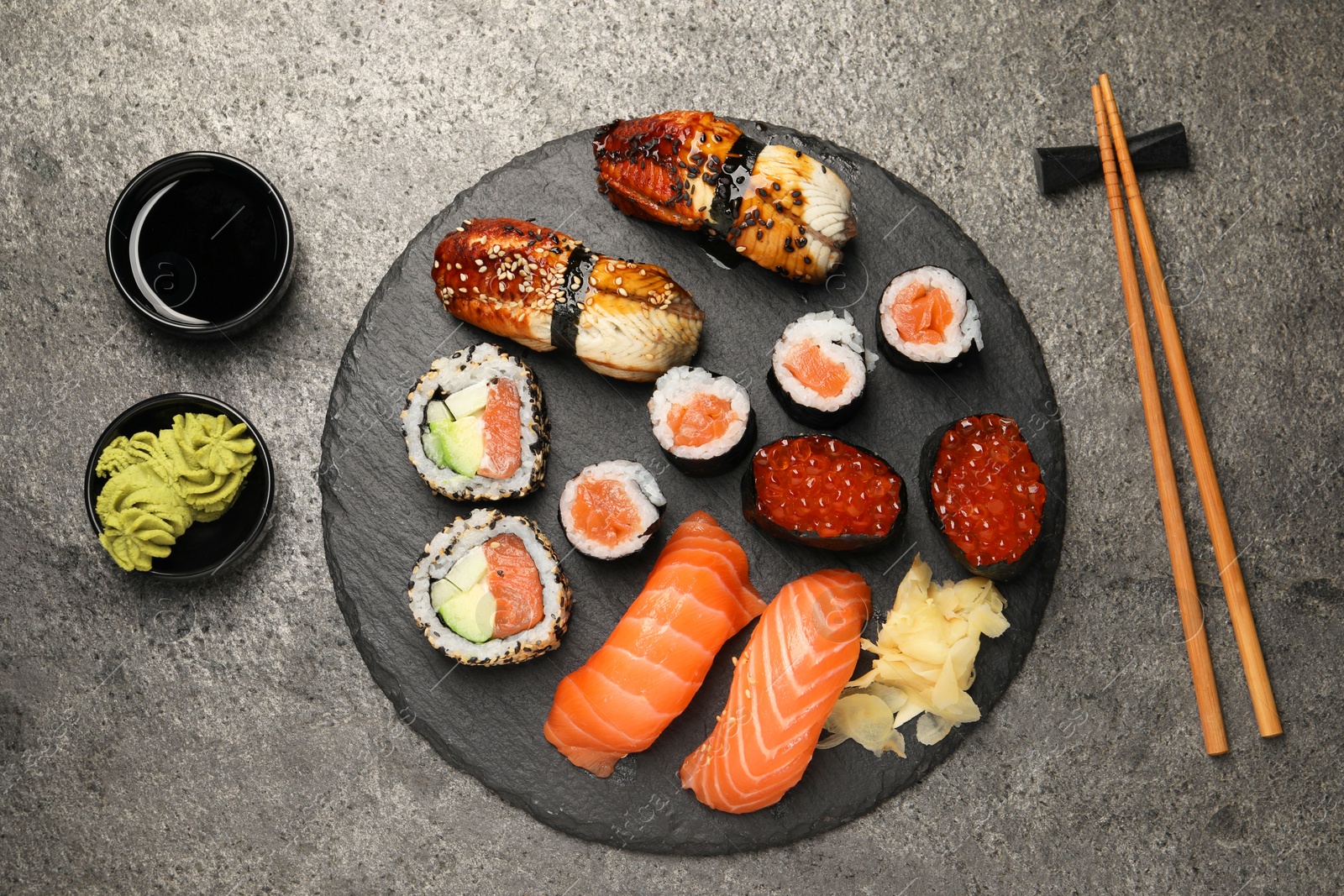 Photo of Set of delicious sushi rolls on dark grey table, flat lay