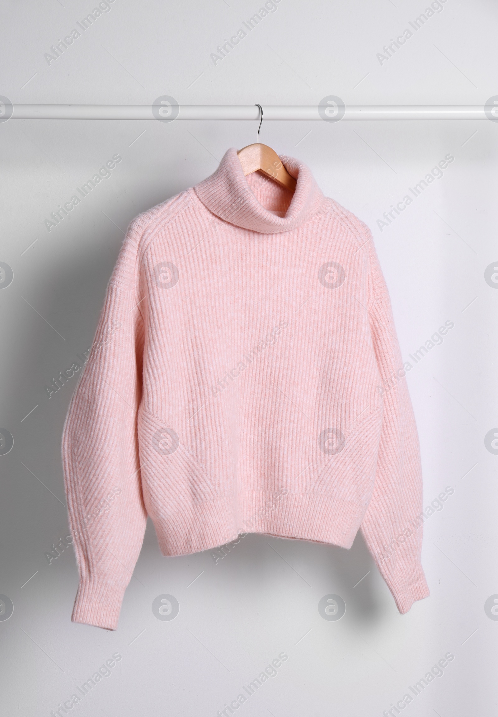 Photo of Warm sweater hanging on rack against white background