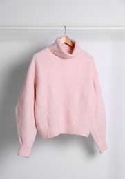 Photo of Warm sweater hanging on rack against white background