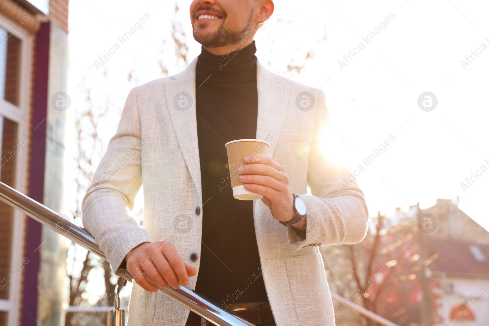 Photo of Businessman with cup of coffee on city street in morning, closeup