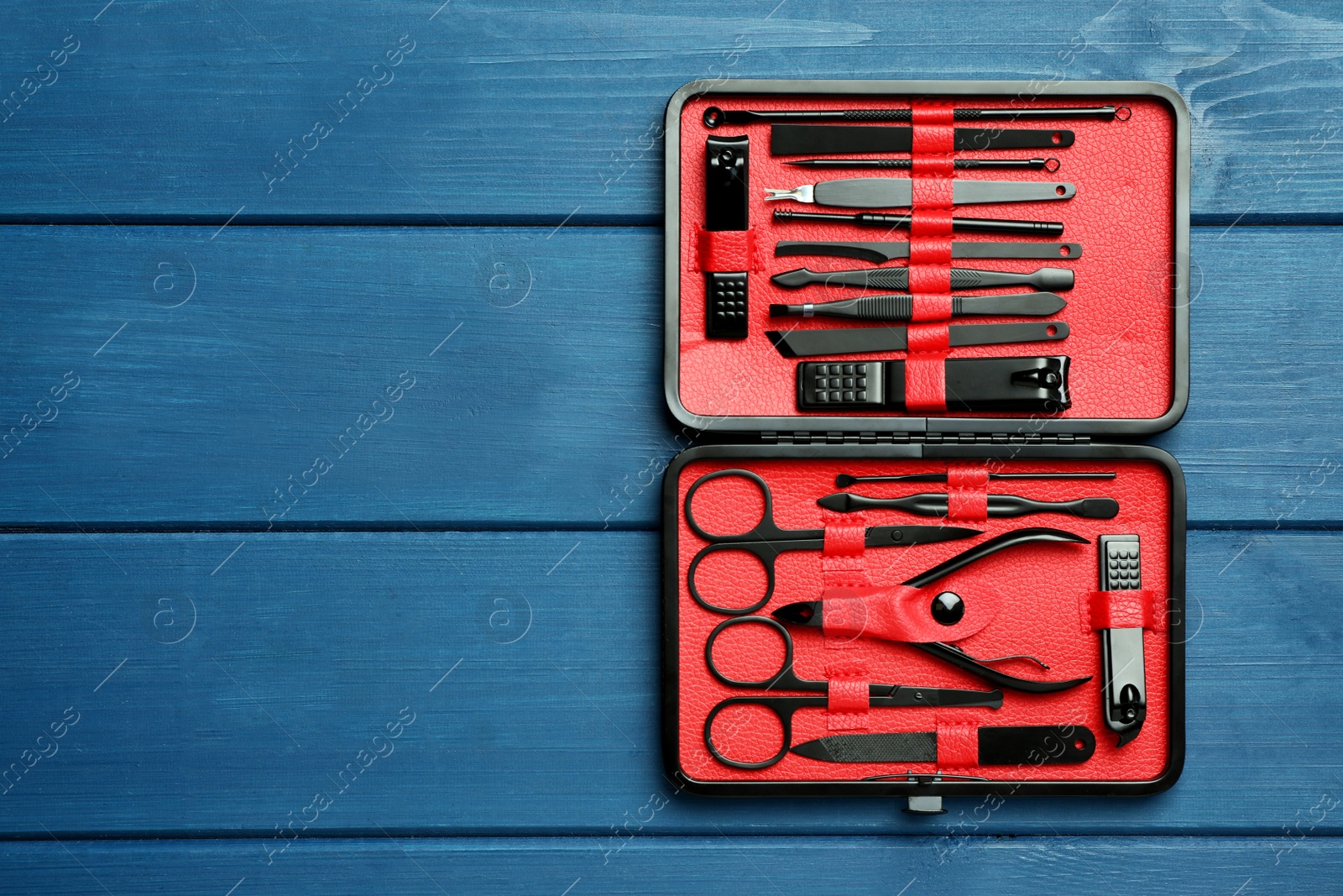 Photo of Manicure set in case on blue wooden table, top view. Space for text