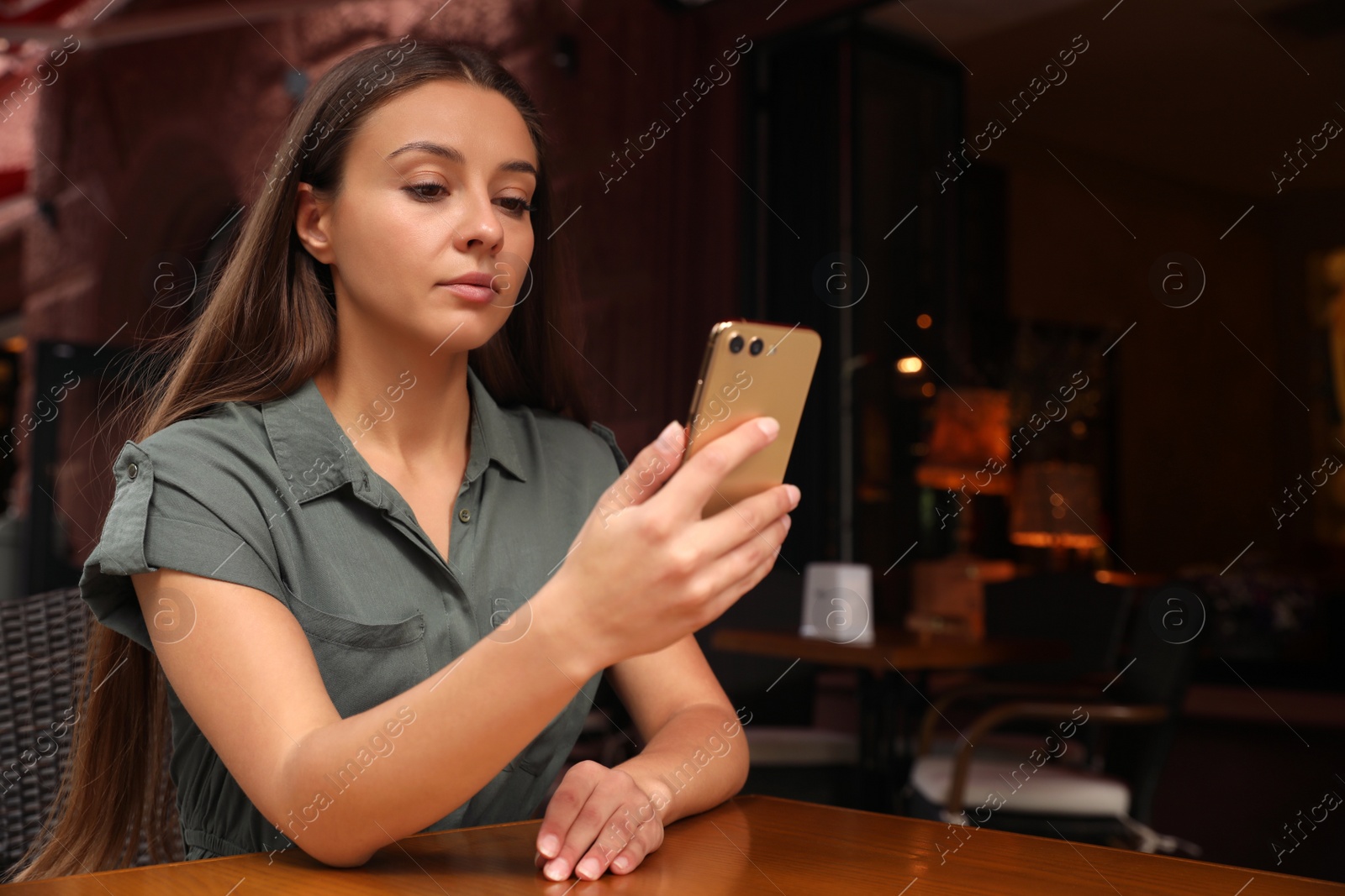 Photo of Young woman unlocking smartphone with facial scanner in outdoors cafe. Biometric verification