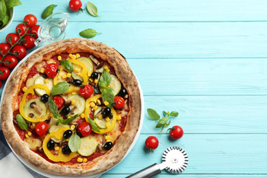 Flat lay composition with vegetable pizza on light blue wooden table. Space for text