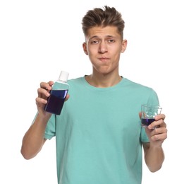 Young man using mouthwash on white background