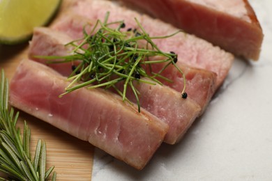 Pieces of delicious tuna steak with microgreens and rosemary on board, closeup